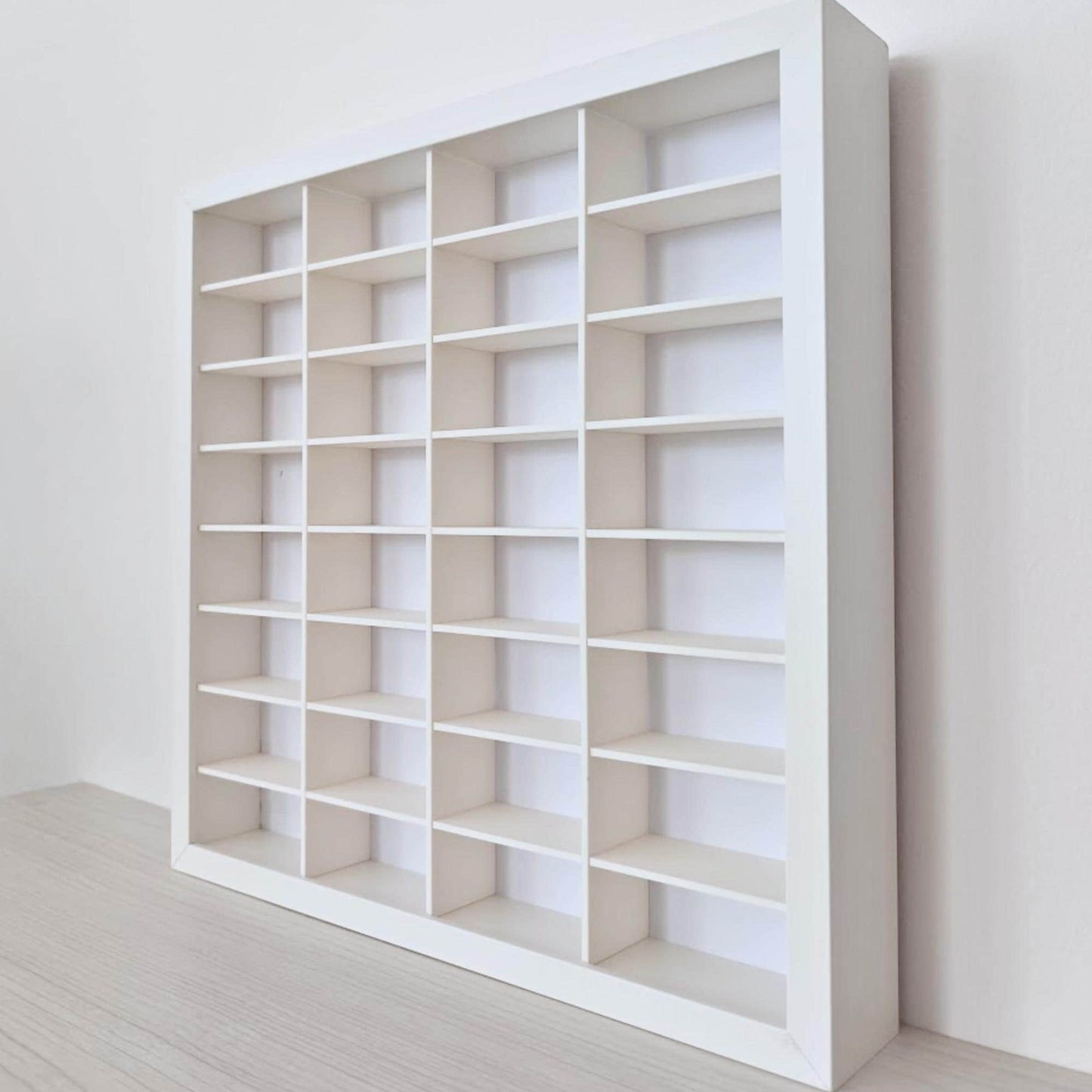 Close side view of the white display frame showing the interlocking horizontal shelves and vertical dividers.