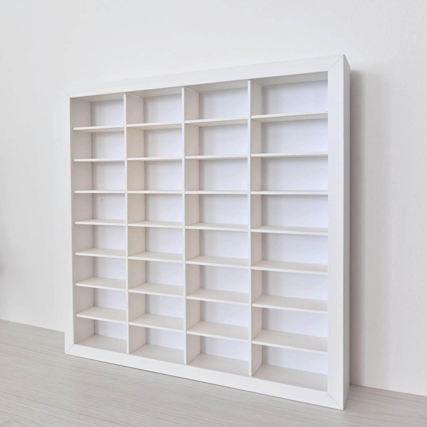 Angled view of the empty 32-compartment grid installed inside the white frame, showing the depth of the shelves.