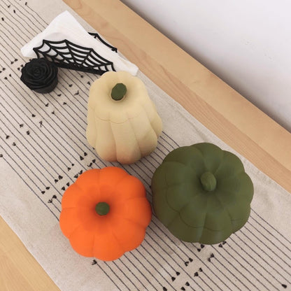 Top view of three pumpkin containers with lids in orange, dark green and desert tan, showing their different shapes and sizes.