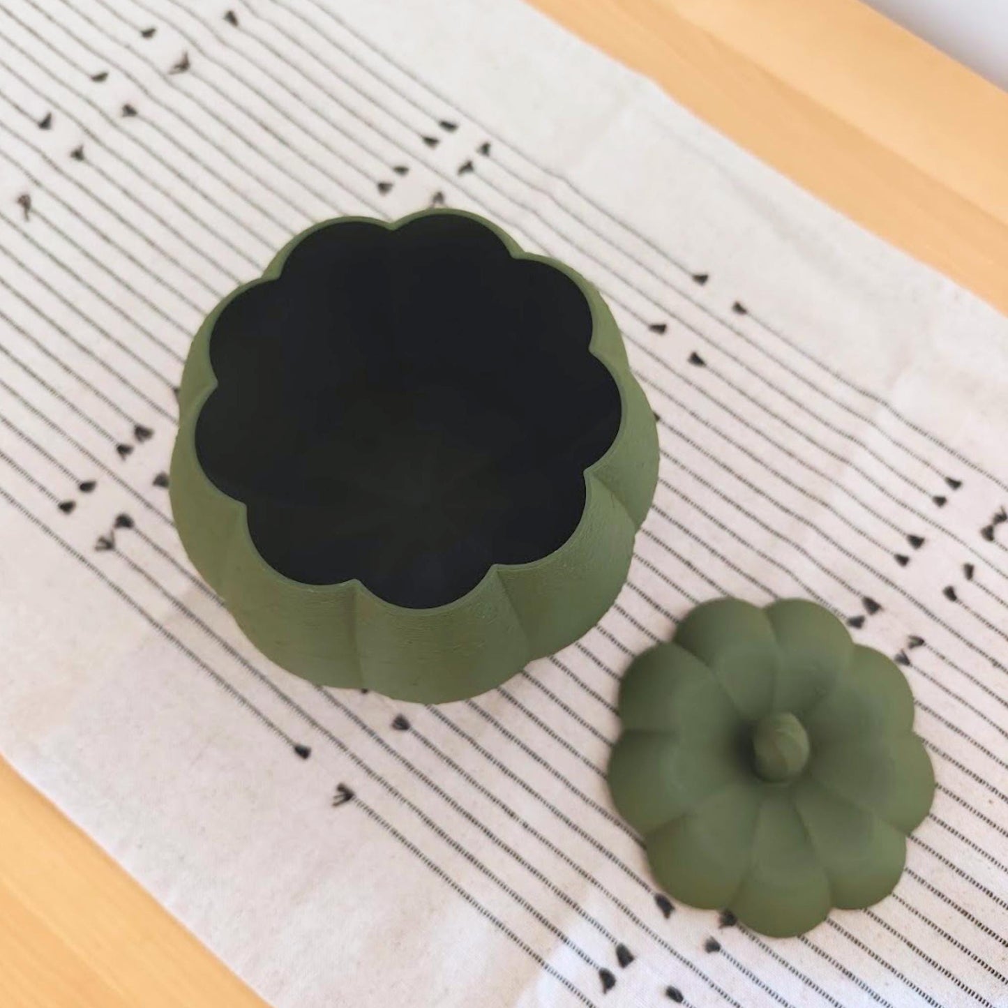 Dark green pumpkin storage container shown open from above with its matching stem lid placed beside it.