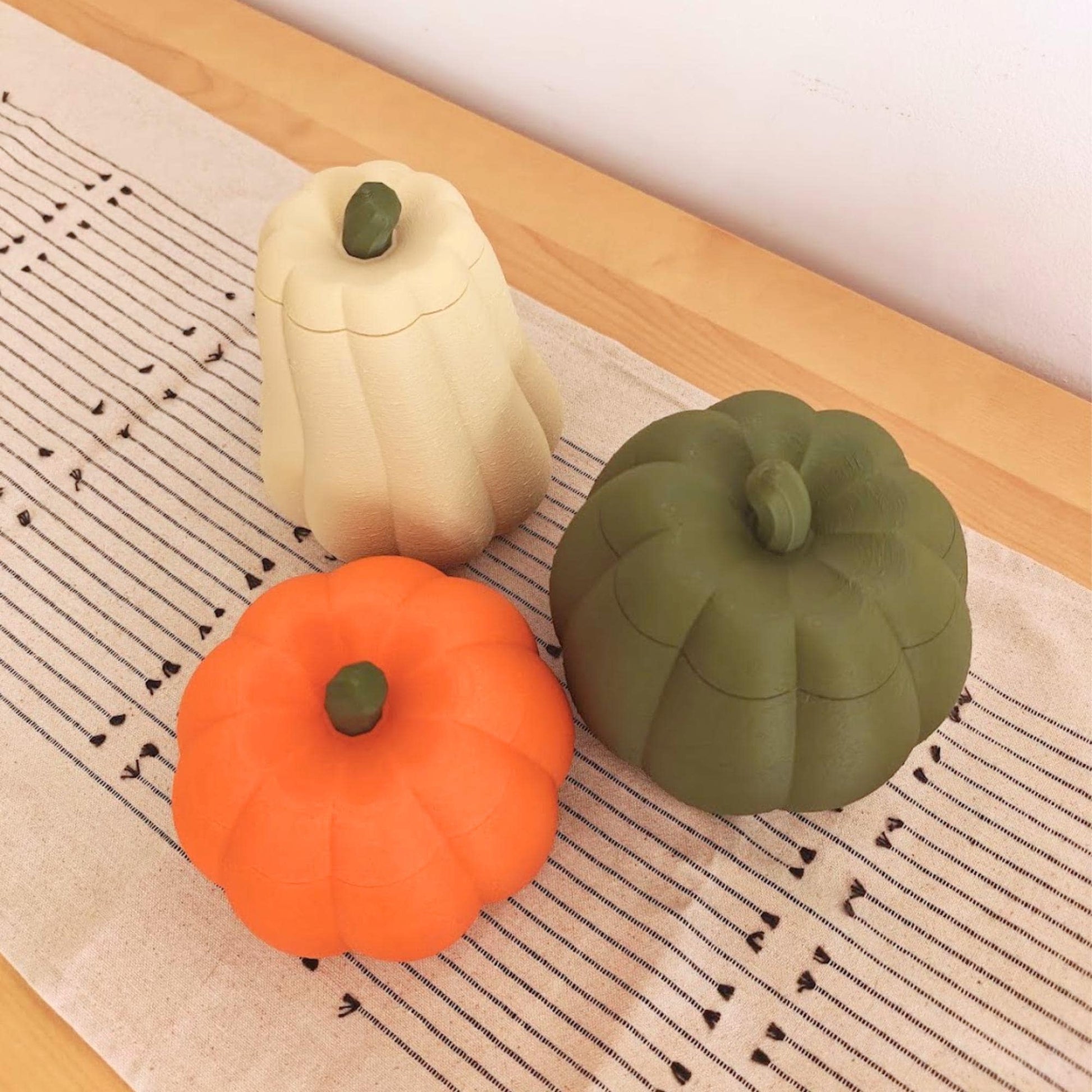 Three pumpkin containers with matching lids in orange, dark green and desert tan, showing the three available shapes.