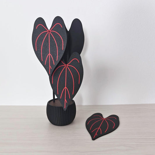 Anthurium Queen of Hearts coaster set with four black leaf coasters and red veins displayed as a decorative potted plant.