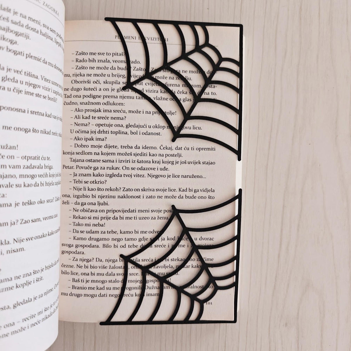 Two spiderweb corner bookmarks placed on the corners of an open book to mark pages