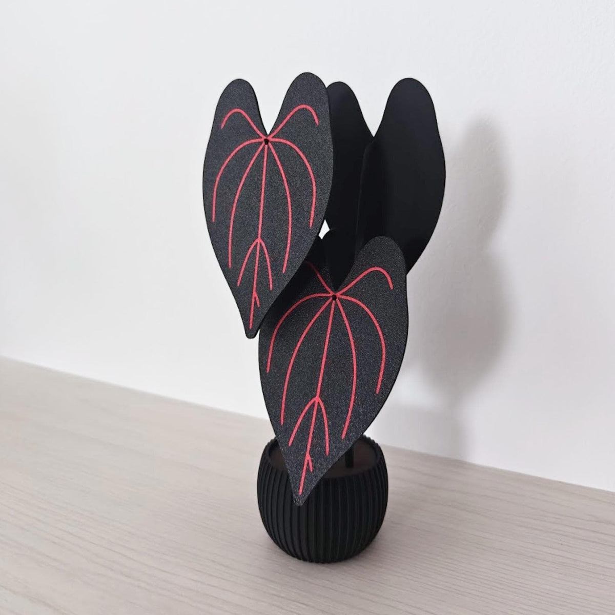 Four-piece Anthurium Queen of Hearts coaster set assembled in a black ribbed pot with red leaf vein details.