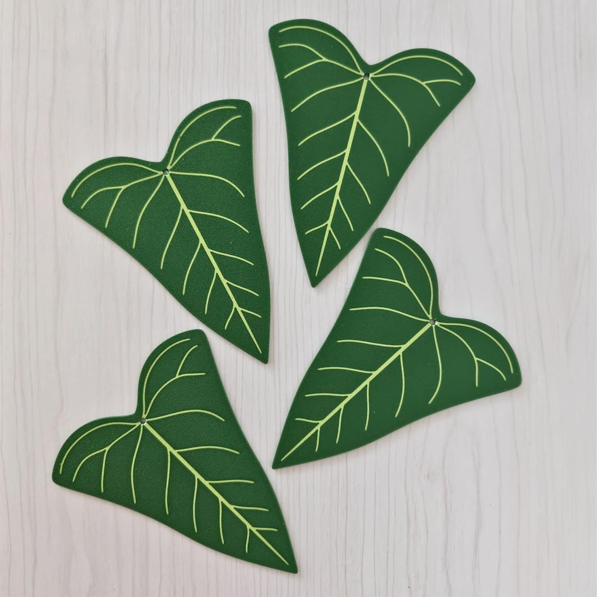 Four Anthurium Delta Force leaf coasters arranged flat on a light wooden surface