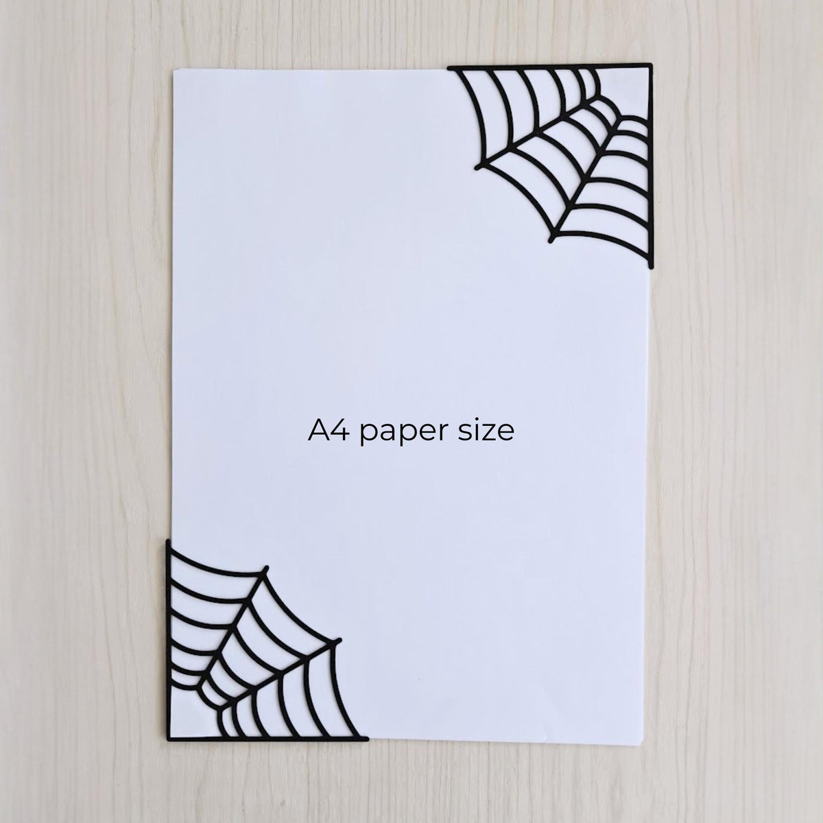 Spiderweb corner bookmarks shown on A4 paper for size comparison