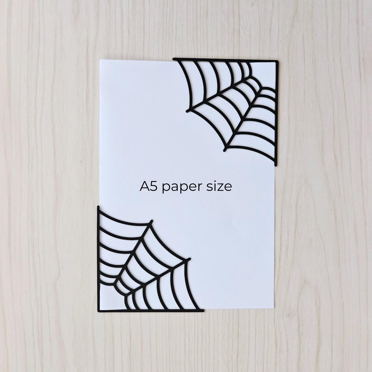 Spiderweb corner bookmarks shown on A5 paper for size comparison