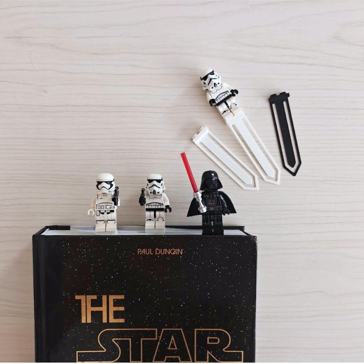 Brick-compatible minifigure bookmark clips displayed on a book with collectible figures