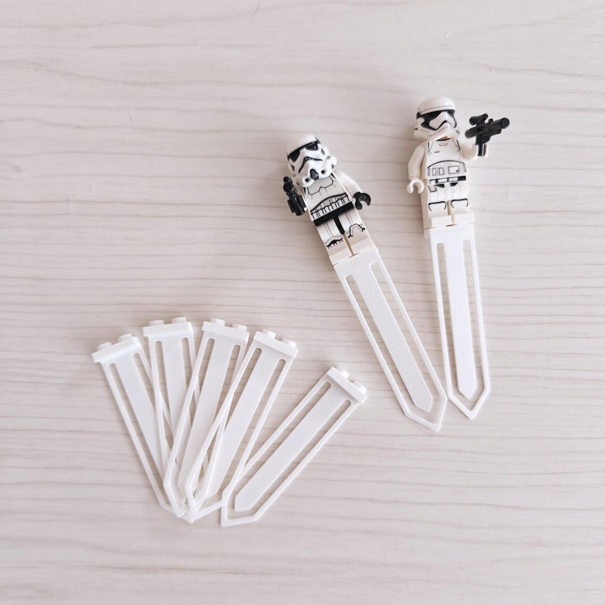 Set of five white bookmark clips with two clips holding brick-style minifigures