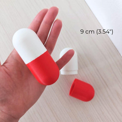 9 cm red and white pill capsule box held in one hand with the removable lid beside it, suitable for tiny gifts or messages.