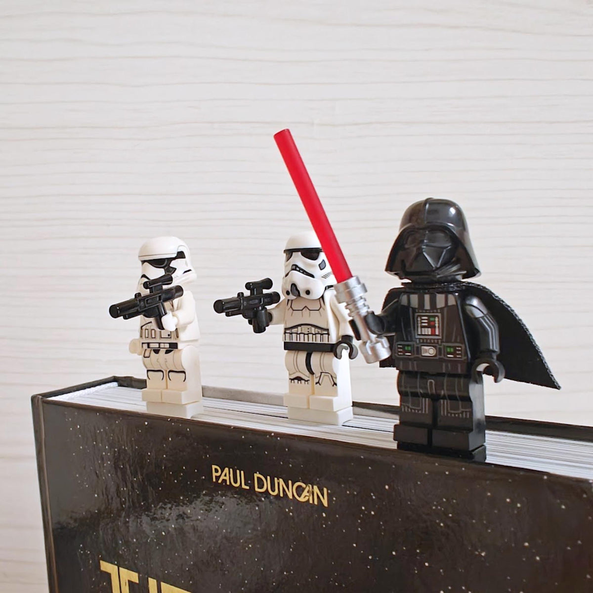 Close-up of brick-compatible bookmark clips with collectible minifigures on a book