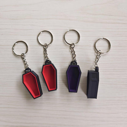 Red and purple coffin keychains showing front and back views
