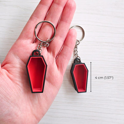 Red coffin keychain shown in hand, measuring 4 cm (1.57 in) long