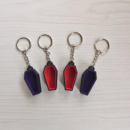 Coffin keychains in red and purple with black outer frames and metal key rings