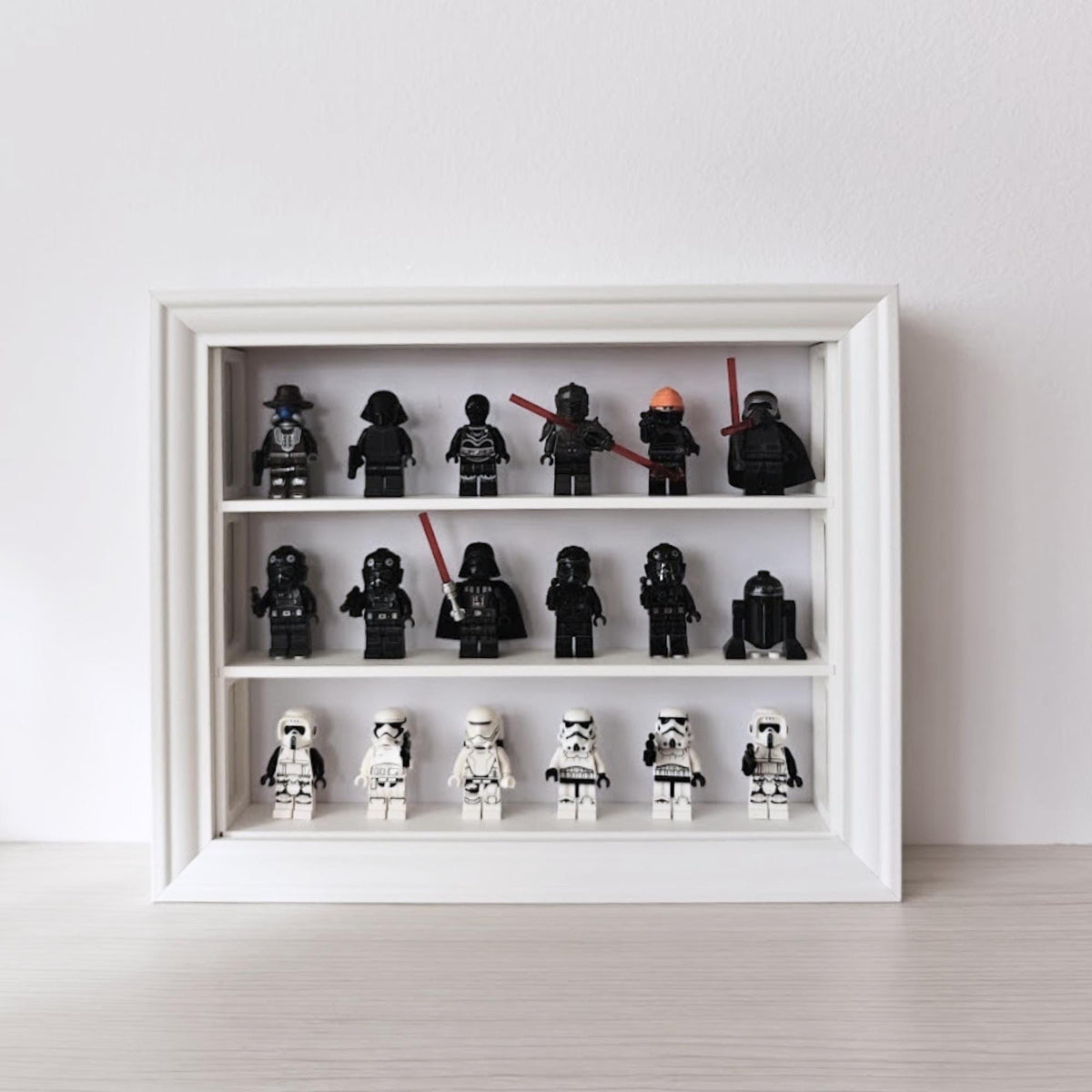 White horizontal VÄSTANHED frame insert displaying black and white LEGO minifigures across three shelves.