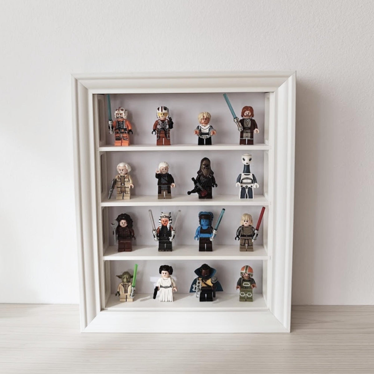Front view of white vertical VÄSTANHED frame shelf insert displaying LEGO minifigures on four rows.