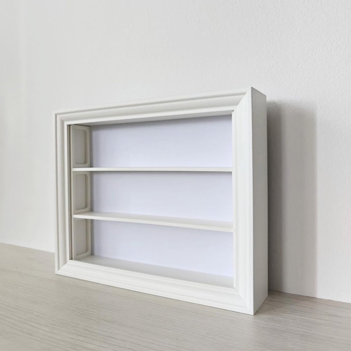 Angled view of empty horizontal IKEA VÄSTANHED frame with three white shelves.