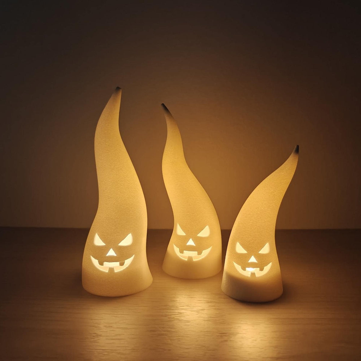 Three white ghost tealight covers with silly faces shown unlit, measuring approximately 11–16 cm high.