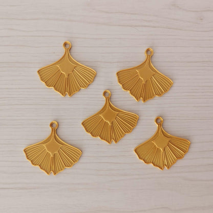 Set of five gold ginkgo leaf ornaments arranged together on a light wooden surface.