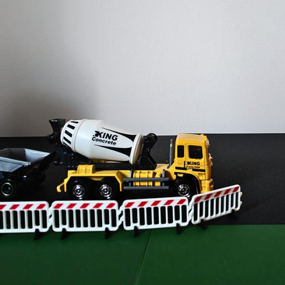 Close-up of miniature road barriers in front of a cement mixer truck