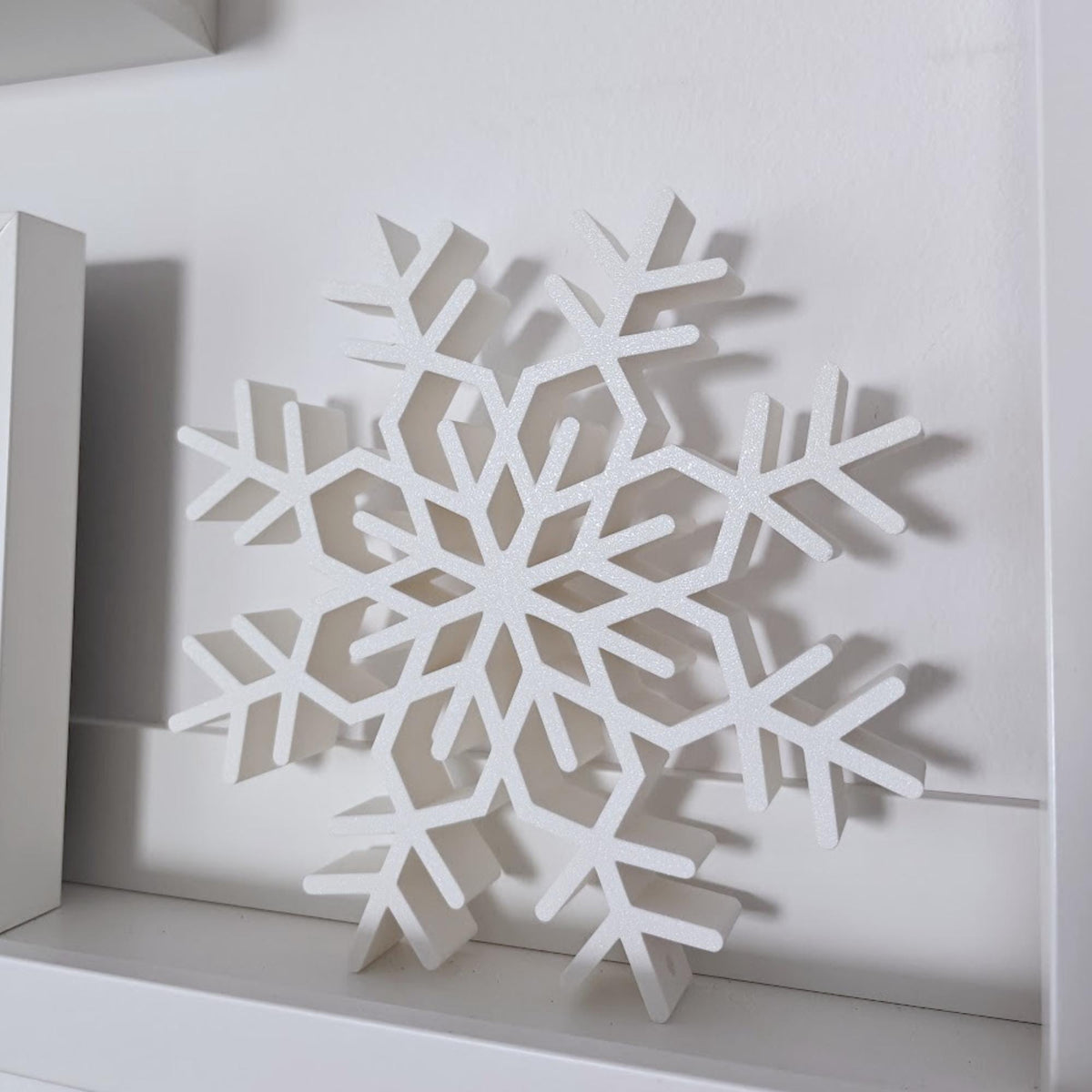 Large white standing snowflake decoration displayed on a modern shelf