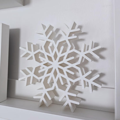 Large white standing snowflake decoration displayed on a modern shelf