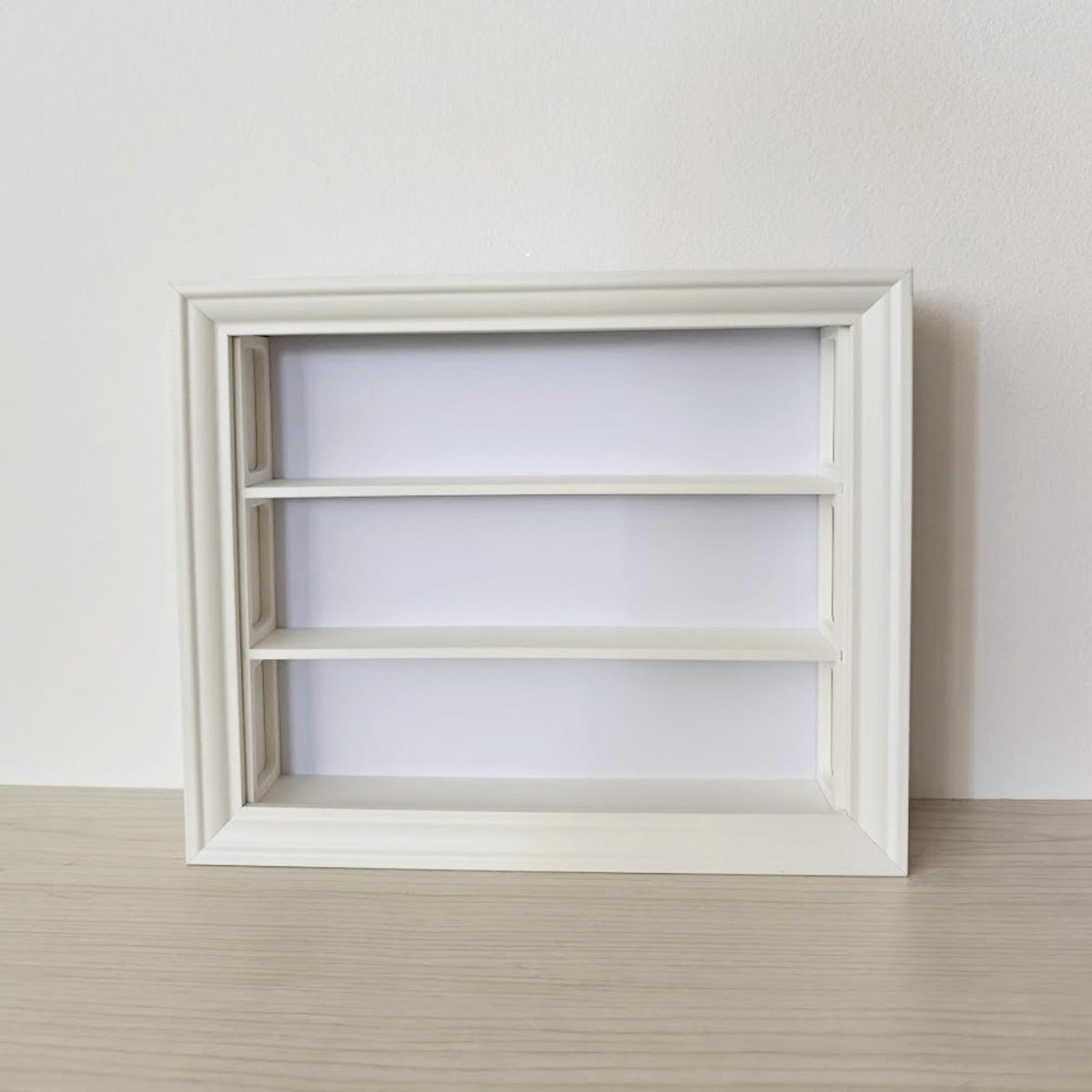 Front view of empty horizontal VÄSTANHED frame insert with three smooth display shelves.