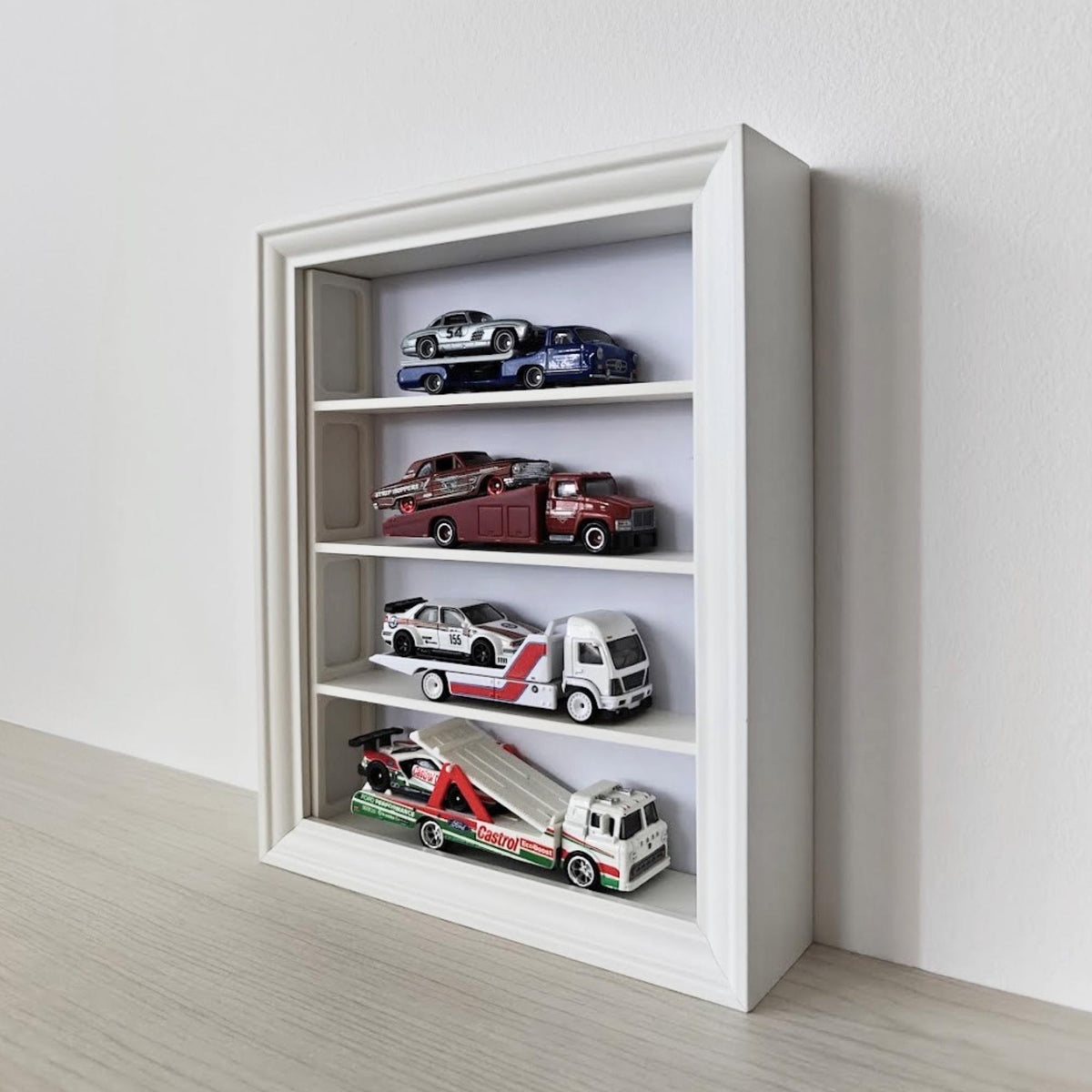 Angled view of vertical IKEA VÄSTANHED frame with white shelves displaying miniature cars.