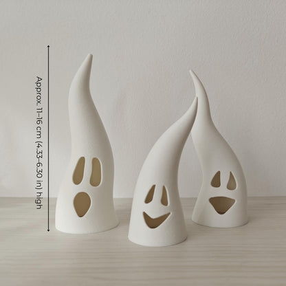 Three white ghost tealight covers with silly faces shown unlit, measuring approximately 11–16 cm high.