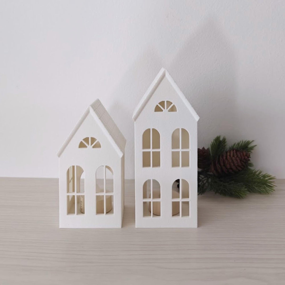 Small and tall decorative house lanterns displayed with winter greenery