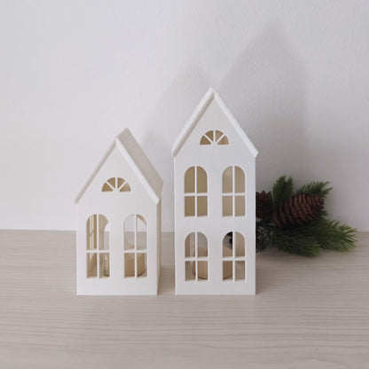 Small and tall decorative house lanterns displayed with winter greenery
